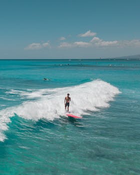 Drone shot of a surfer on a wave in the turquoise waters of Hawaii.