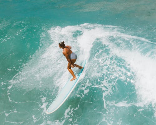 Woman in Black Bikini Holding White Surfboard on Body of Water