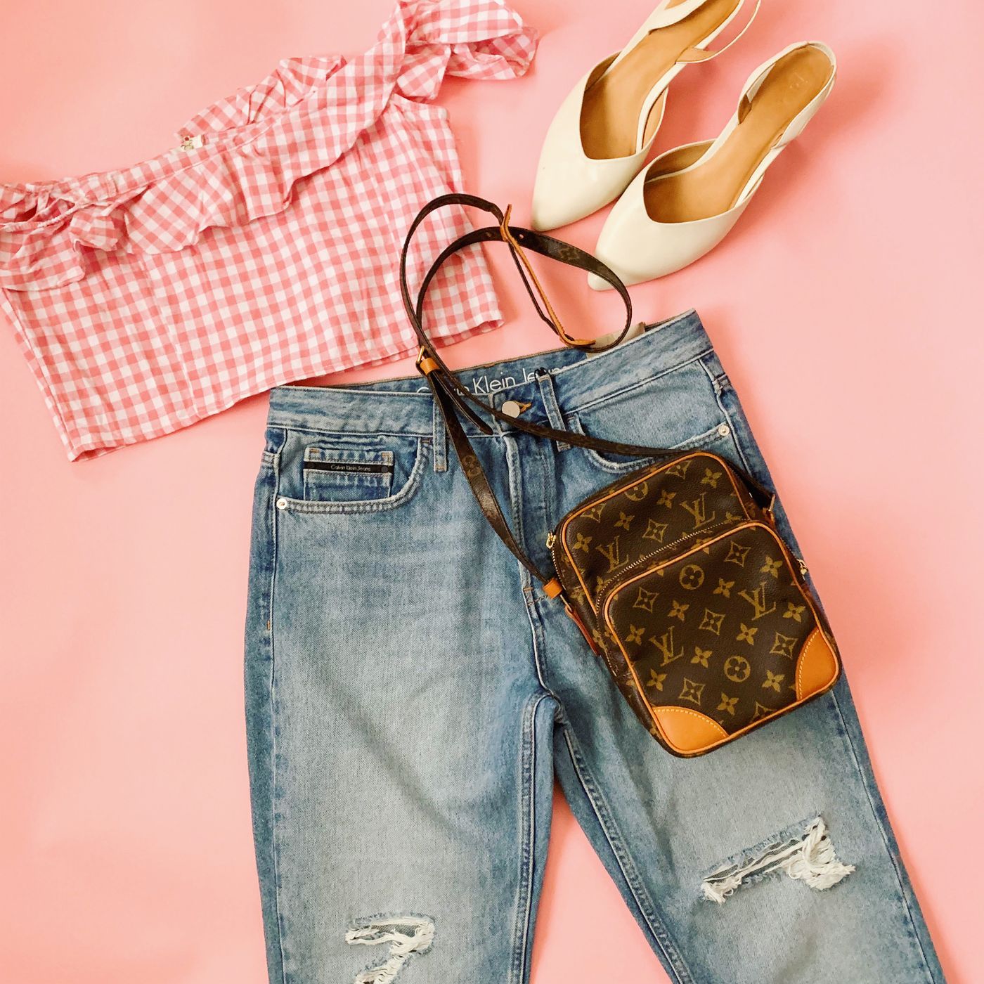Fashion outfit flat lay with denim and accessories on a soft pink background without people