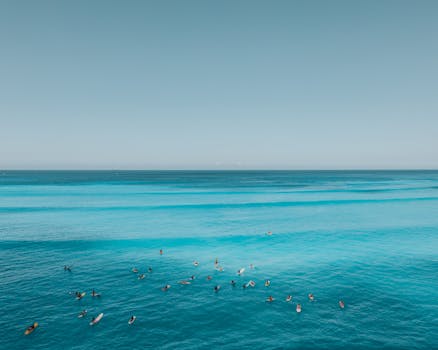 Aerial shot of surfers enjoying the vibrant turquoise waters of a Hawaiian beach under a clear sky.