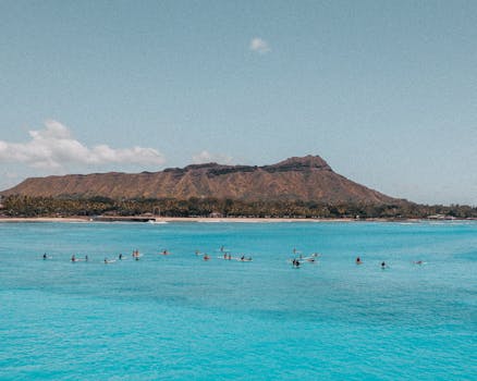 Aerial view of surfers enjoying the waves with Diamond Head in the backdrop, Hawaii.