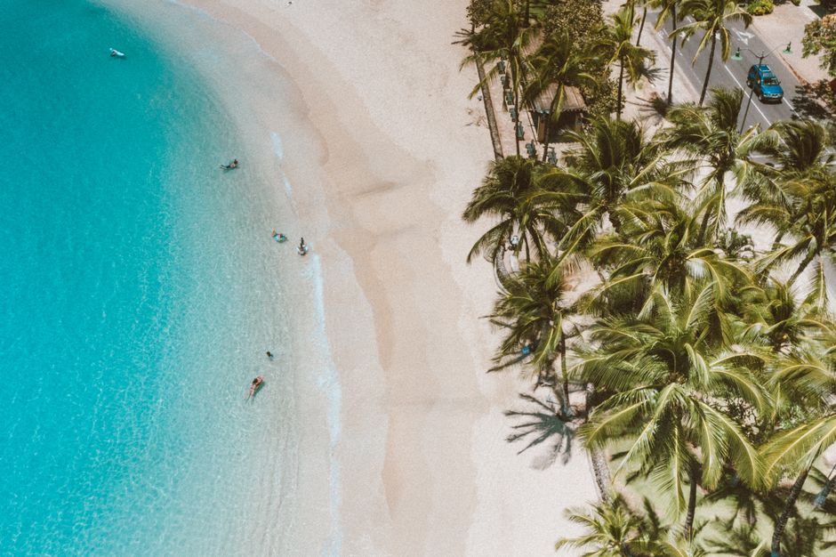 Stunning Waikiki Sunset - 50 Min Helicopter Tour - Doors Off or On Review Review 2026 - Captivating aerial shot of a Hawaiian beach with turquoise waters and palm trees.
