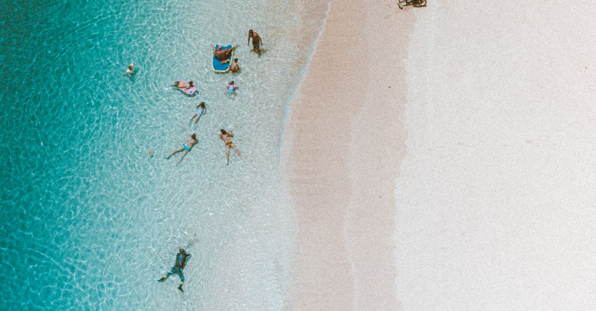 Aerial view of a vibrant Hawaiian beach with people enjoying the clear blue waters and sandy shores.