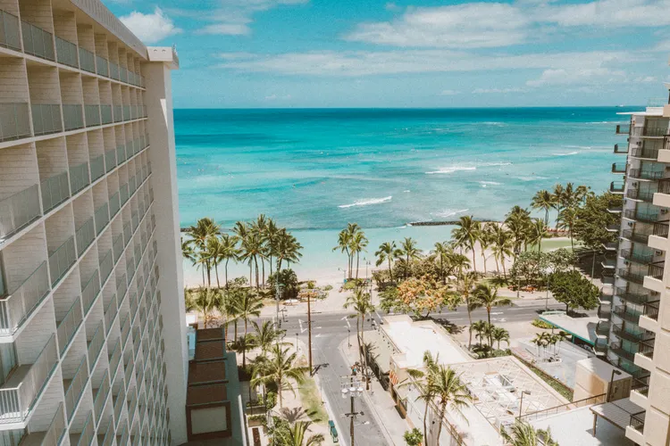 View of Waikiki Beach and palm trees from a high-rise vacation rental balcony on Oahu
