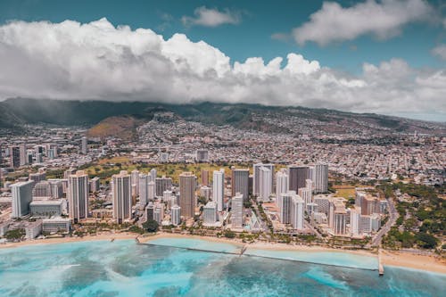 Aerial View of City Buildings Near Body of Water Under Cloudy Sky