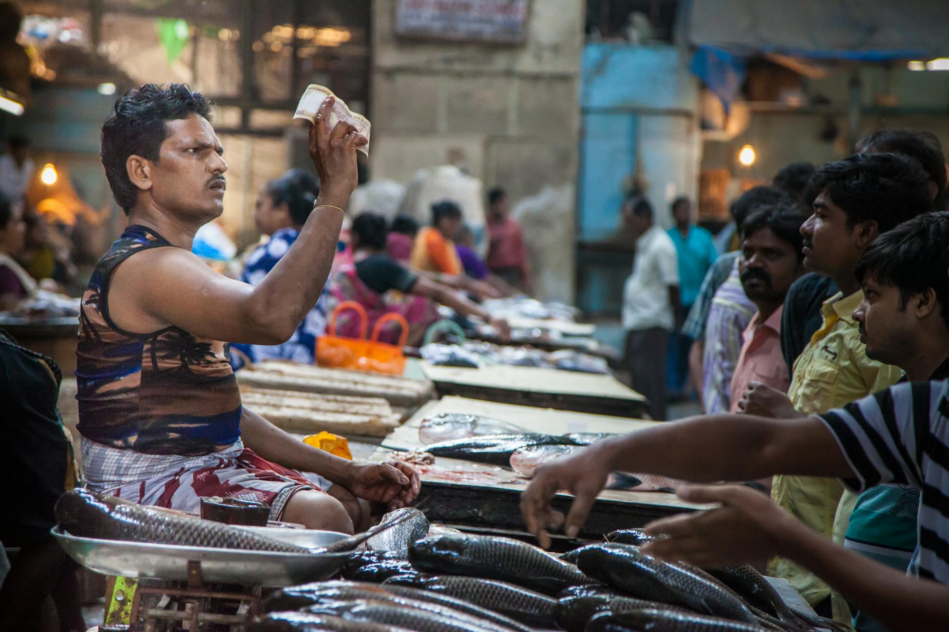 An engaging scene of vendors and customers at a bustling fish market in Mumbai, India.