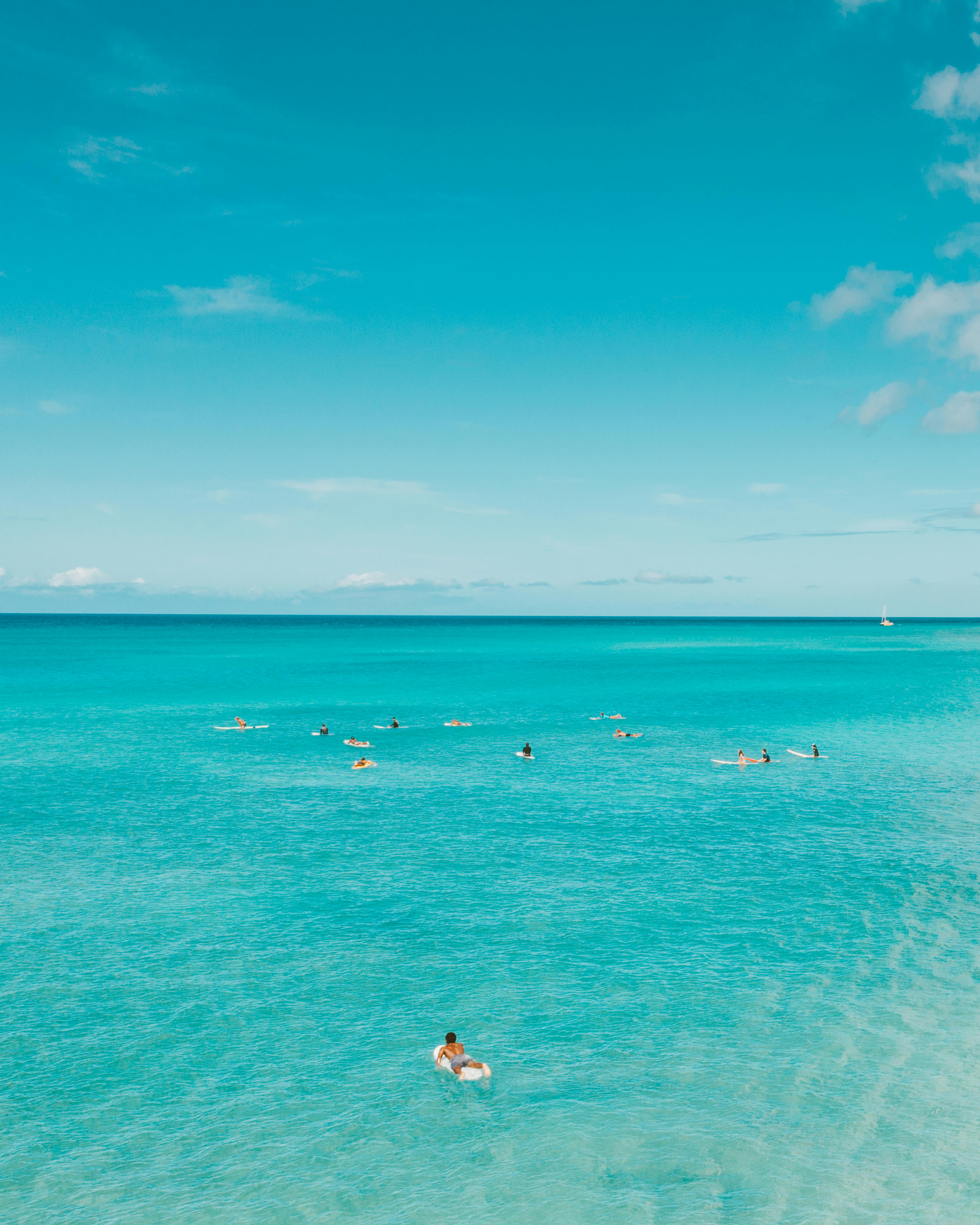 在明亮的天空下，一群冲浪者正享受着夏威夷清澈的蓝色海洋