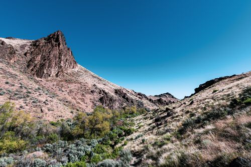 Free Picturesque view of high bristly mounts with growing grass and pointed peak under colorful sky Stock Photo