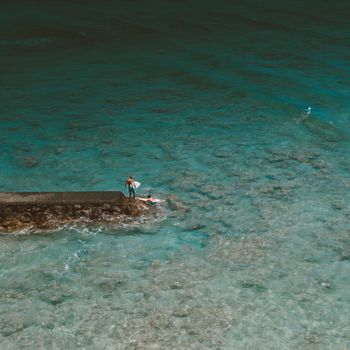从空中俯瞰，夏威夷海岸线附近，冲浪者在清澈碧绿的海水中逐浪