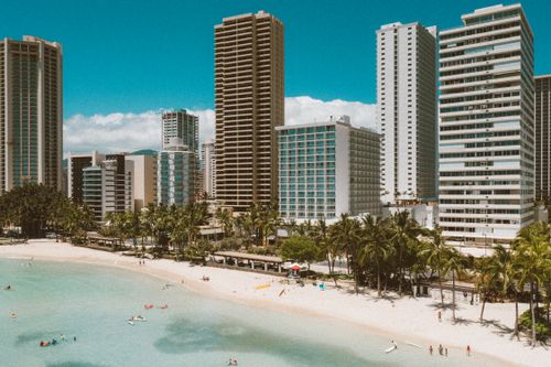 Free Charming aerial view of Waikiki Beach with towering hotels and clear turquoise water under a sunny sky. Stock Photo