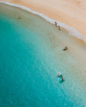 A serene aerial shot of Waikiki Beach, showcasing swimmers and turquoise water under the sun.
