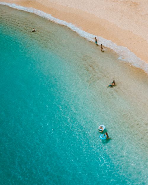 Free A serene aerial shot of Waikiki Beach, showcasing swimmers and turquoise water under the sun. Stock Photo