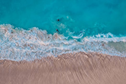Stunning aerial view of turquoise waves hitting a sandy beach in Hawaii, ideal for travel content.