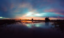 平静的河面上映着宁静的日落，天空倒影色彩缤纷，营造出和平与宁静的氛围