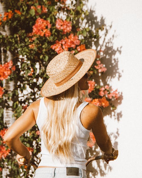 Free Woman in White Tank Top and Brown Straw Hat Standing Near Green Leaf Plant Stock Photo
