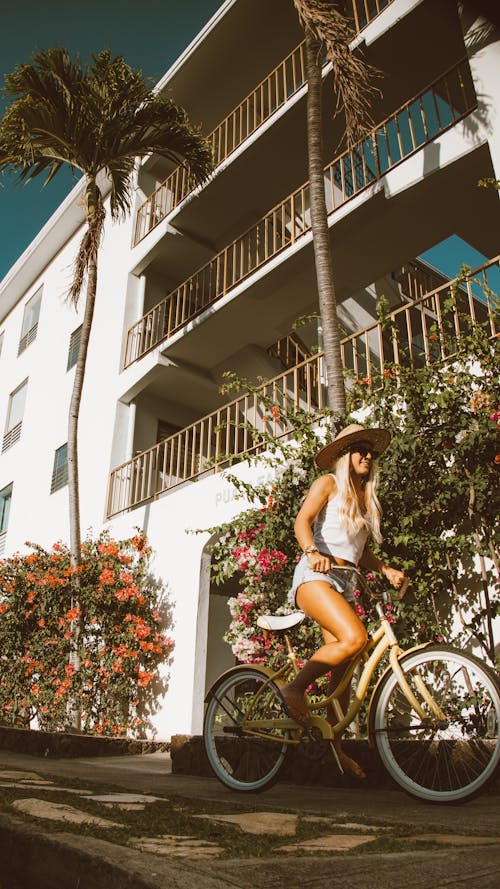 Free Woman in White Tank Top and Blue Denim Shorts Riding on Bicycle Stock Photo