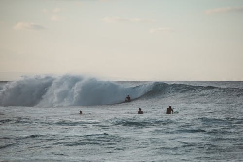 People Surfing on Sea Waves under the Sky