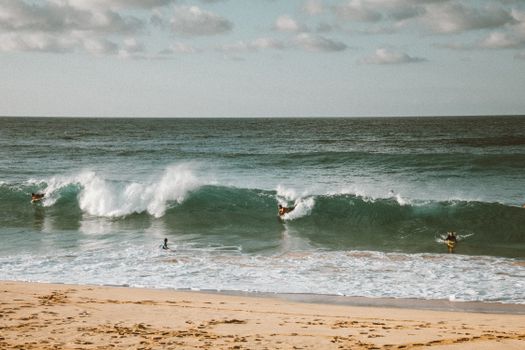 Surfers ride the waves on a sunny day at the beach. Perfect for vacation vibes.
