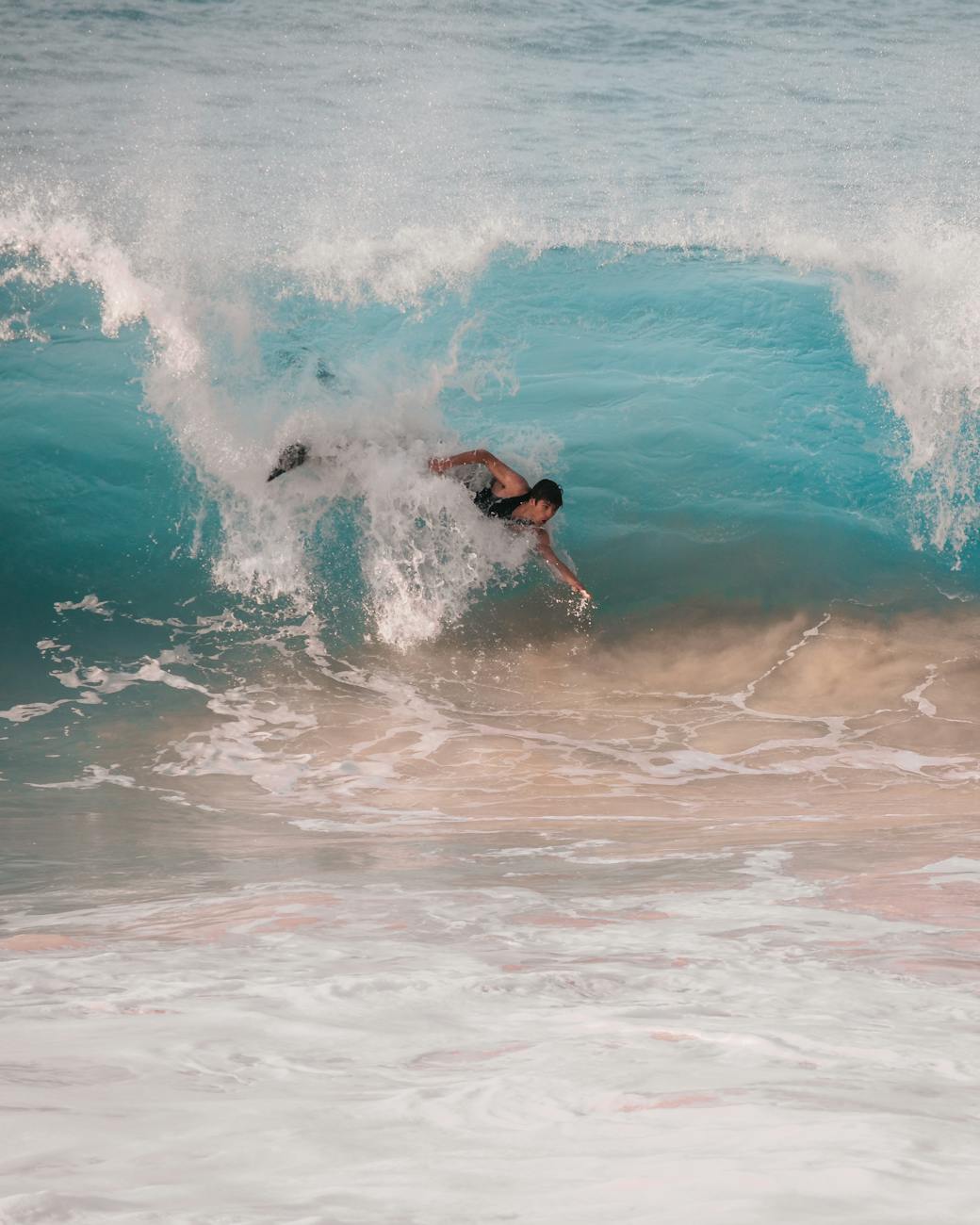 Dynamic capture of a surfer skillfully riding a crashing wave at the beach under bright daylight.
