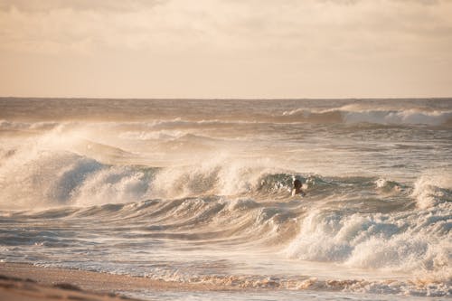 Person Swimming on Ocean Waves Crashing on Shore