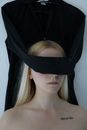 Unrecognizable blindfolded woman with tattoo on chest