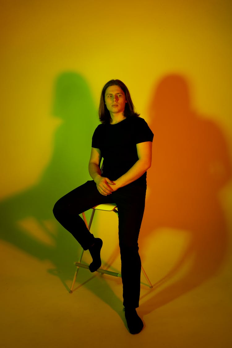 Man In Black Clothes Sitting On Colorful Background