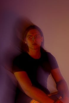 Young pondering male with split personality sitting near wall and looking away in evening