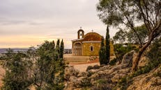 日落时分，一座风景如画的塞浦路斯历史教堂被树木和岩石环绕