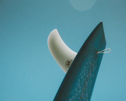 Close-up of a surfboard fin against a clear blue sky, capturing a sunny Hawaiian vibe.