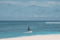 Woman in White and Blue Dress Holding White Surfboard on Beach