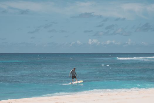 Woman in White and Blue Dress Holding White Surfboard on Beach