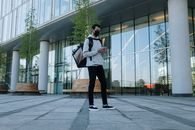 一名蒙面快递员在现代都市建筑间递送包裹