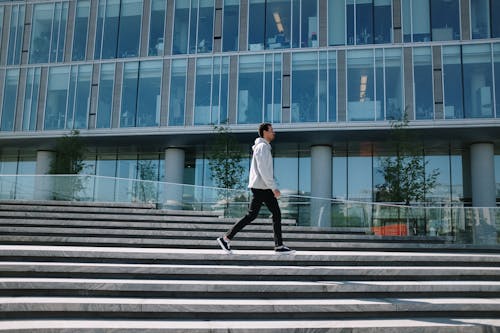 Man in White Long Sleeve Shirt and Black Pants Walking on Gray Concrete Stairs