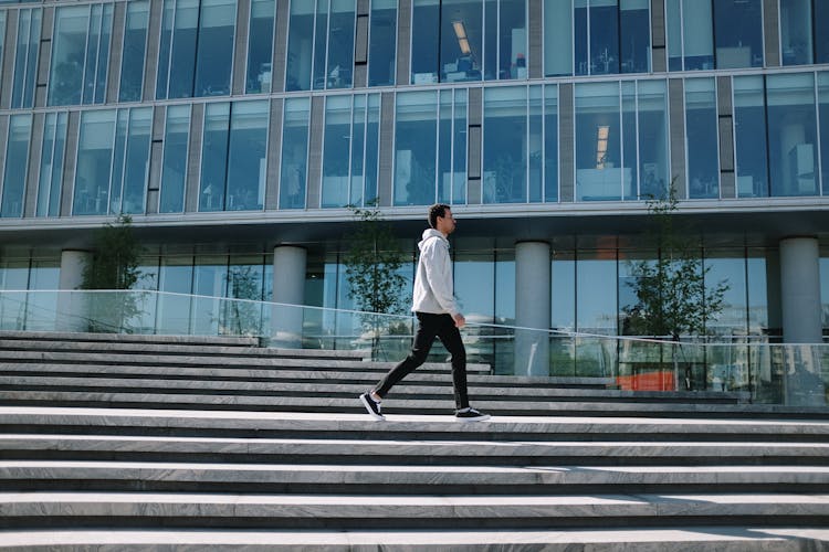 Man In White Long Sleeve Shirt And Black Pants Walking On Gray Concrete Stairs