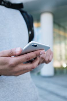 Close-up of hands holding a smartphone outdoors, focused on the device.