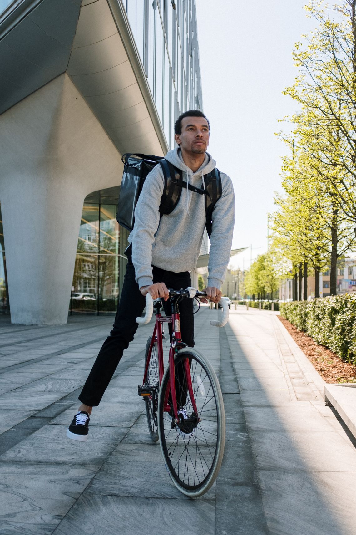 Urban cyclist riding a red bicycle through a modern city district