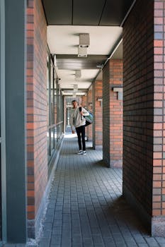 Courier in urban brick passageway carrying delivery bag.