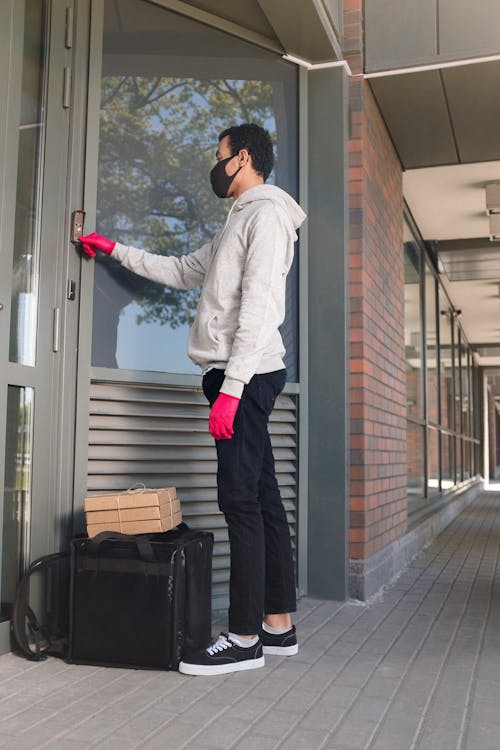 Man in White Dress Shirt and Black Pants Standing Beside Glass Door