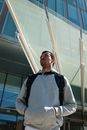 一名背着背包的黑人，正在城市中的现代建筑附近准备交付