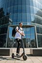 一名男子骑着电动滑板车在市区办公楼外送货