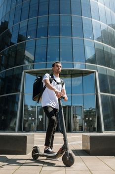 一名男子骑着电动滑板车在市区办公楼外送货