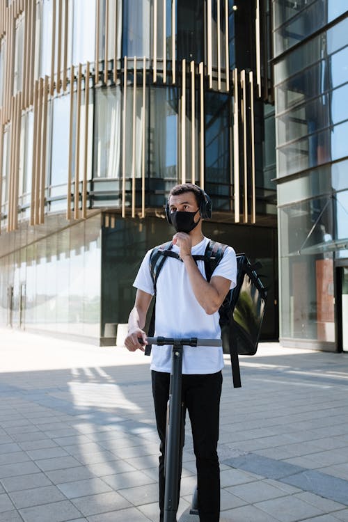 Man in White Shirt and Black Pants Wearing Black Sunglasses Standing on Sidewalk