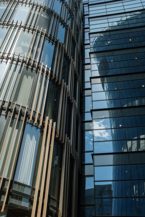 Free Close-up of two modern glass skyscrapers with unique window designs reflecting the cityscape. Stock Photo