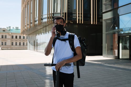 Man in Blue Polo Shirt and Black Backpack Standing on Sidewalk