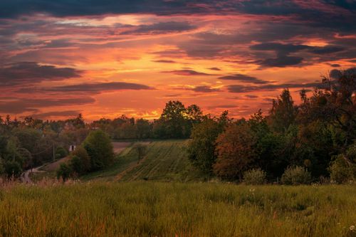 Free Breathtaking view of a vibrant sunset casting warm hues over a lush, green landscape. Stock Photo