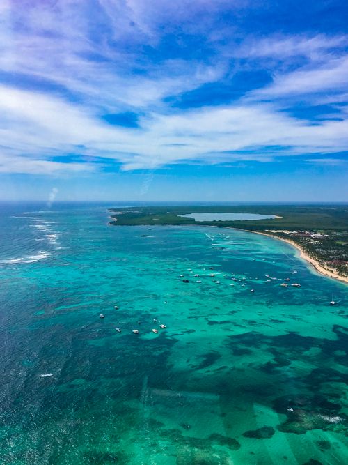 Free Drone view of spectacular seascape with azure shallow sea washing lush forested coast on sunny clear day Stock Photo