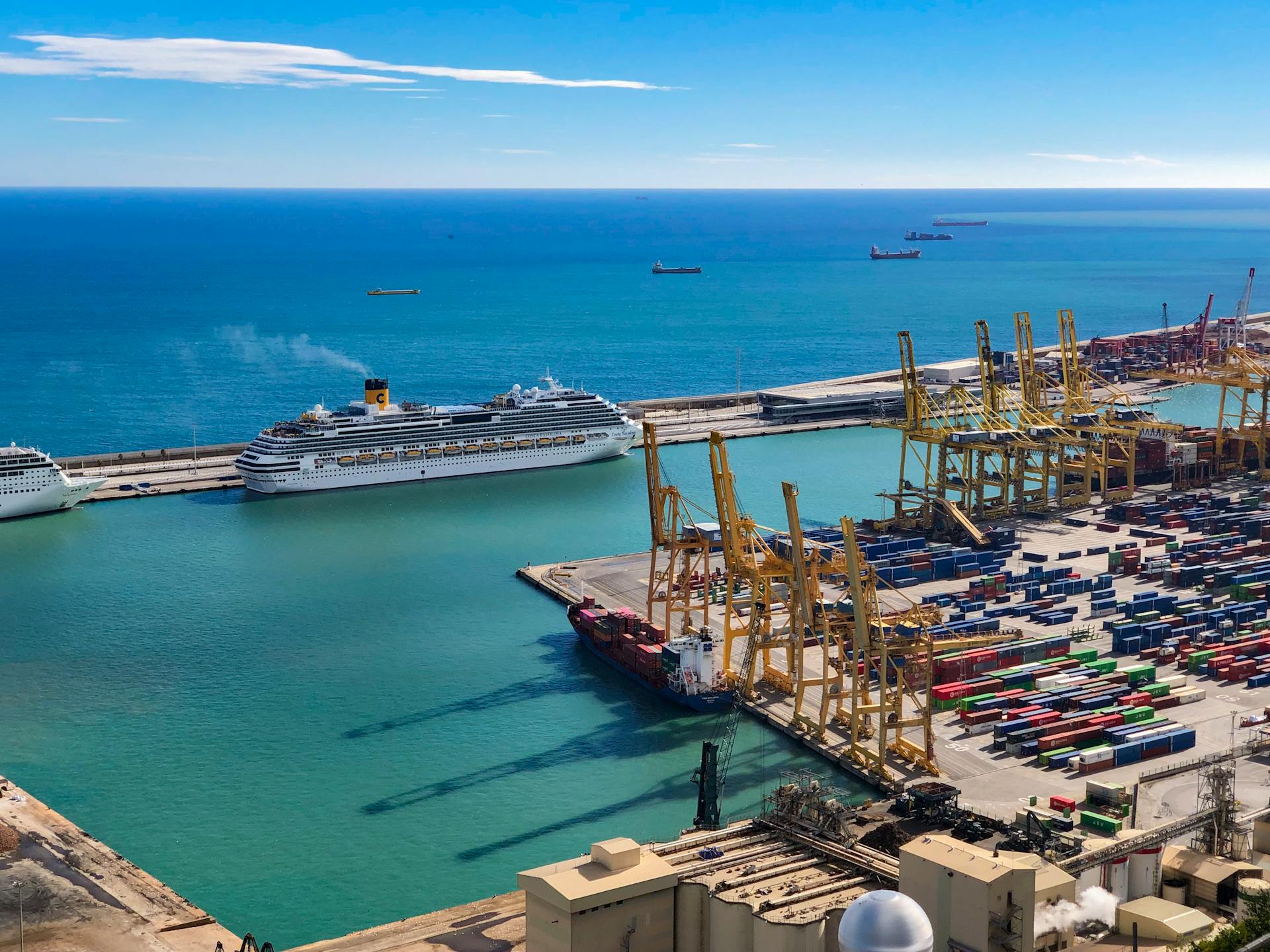 Scenic view of cargo containers and cruise ship at a harbor under blue skies.