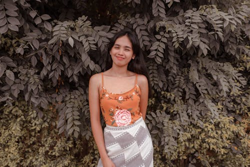 Positive Asian woman near green fence