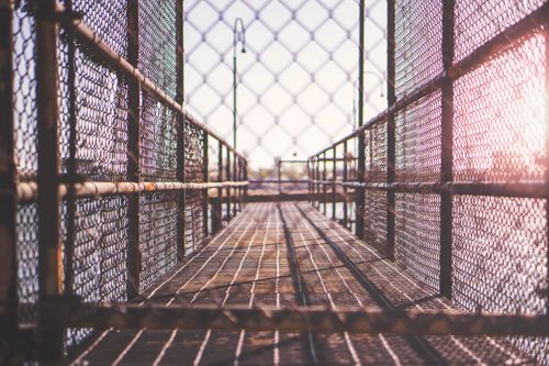 Free A rustic metal fence walkway captures the afternoon sunlight, creating a dramatic perspective. Stock Photo