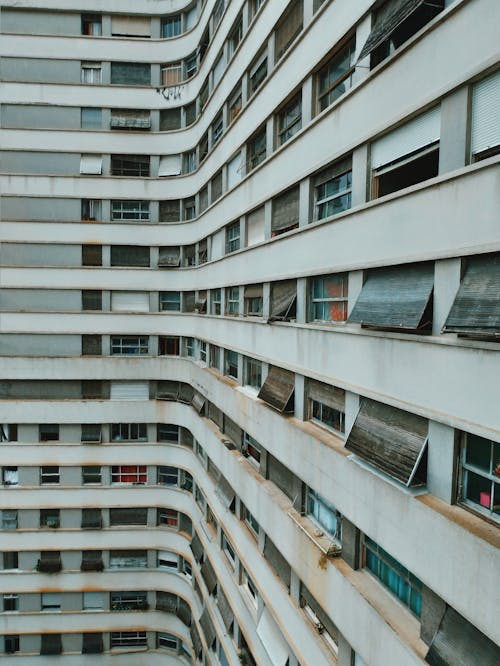 Contemporary high rise apartment complex with old narrow rectangle glass windows and rolling shutters